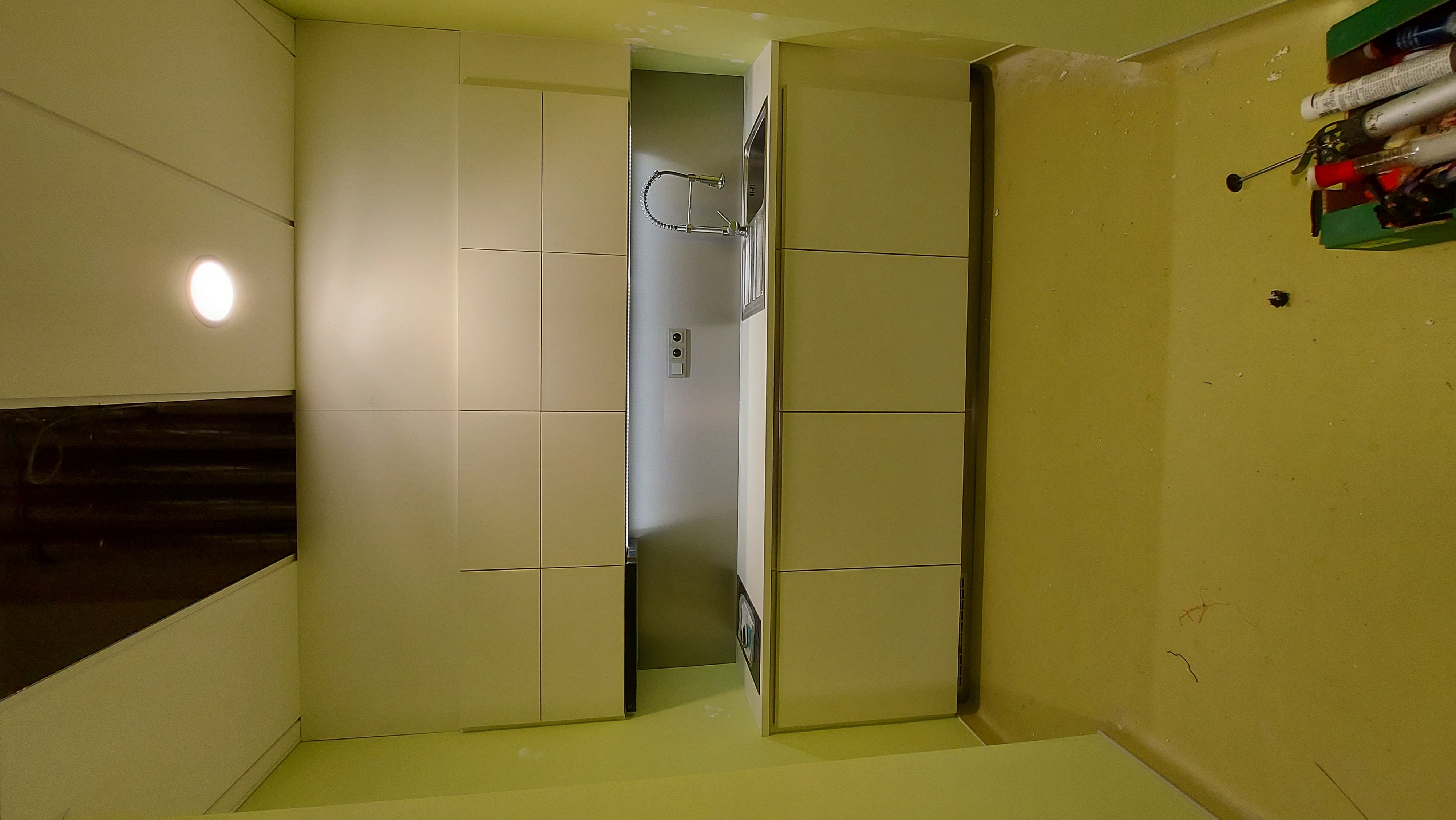 Kancelářská kuchyňka s krémovými dvířky, nerezovou zástěnou a osvětlením pod skříňkami