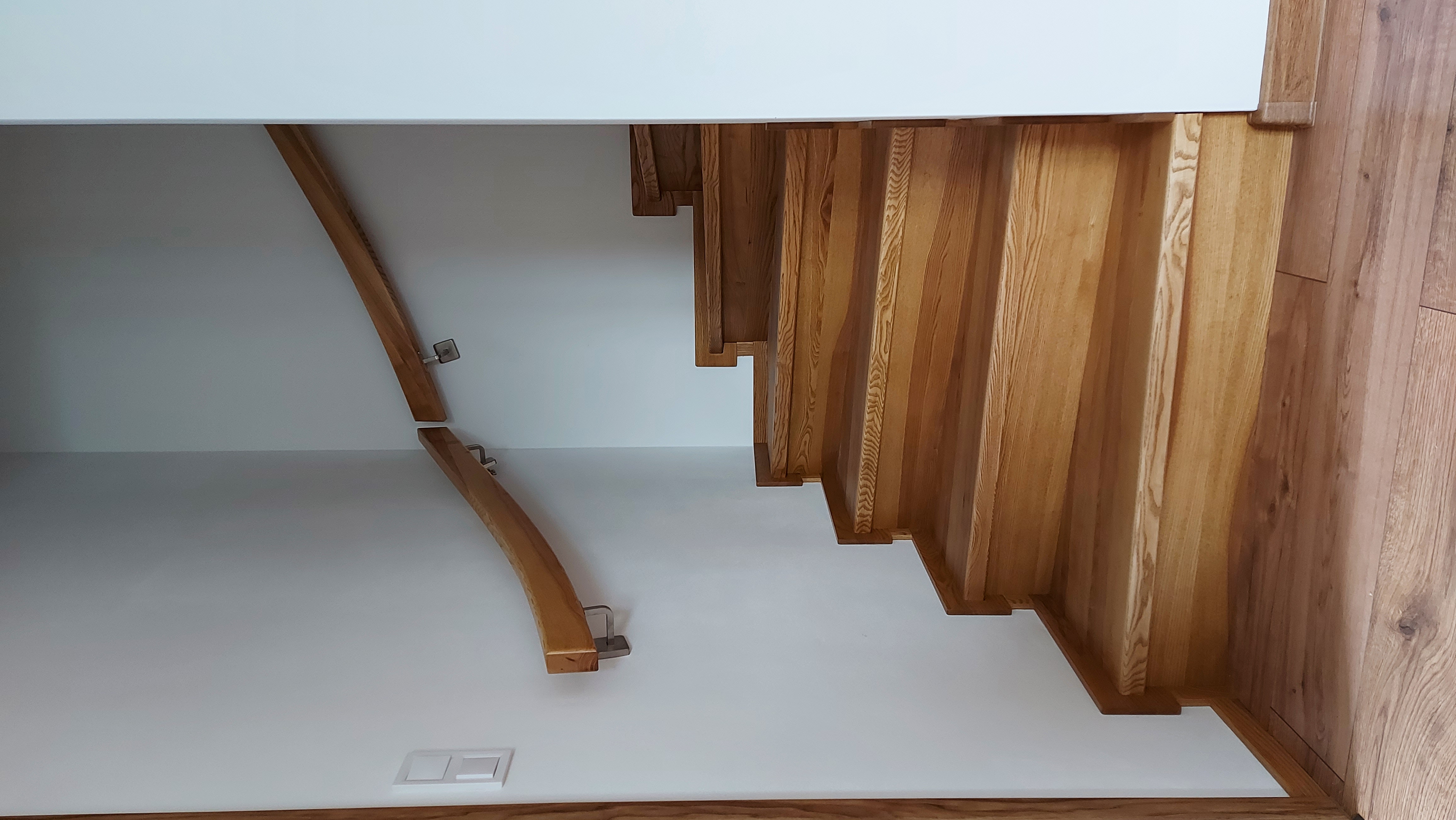 Obkladové schodiště z jasanu s madlem na stěně
