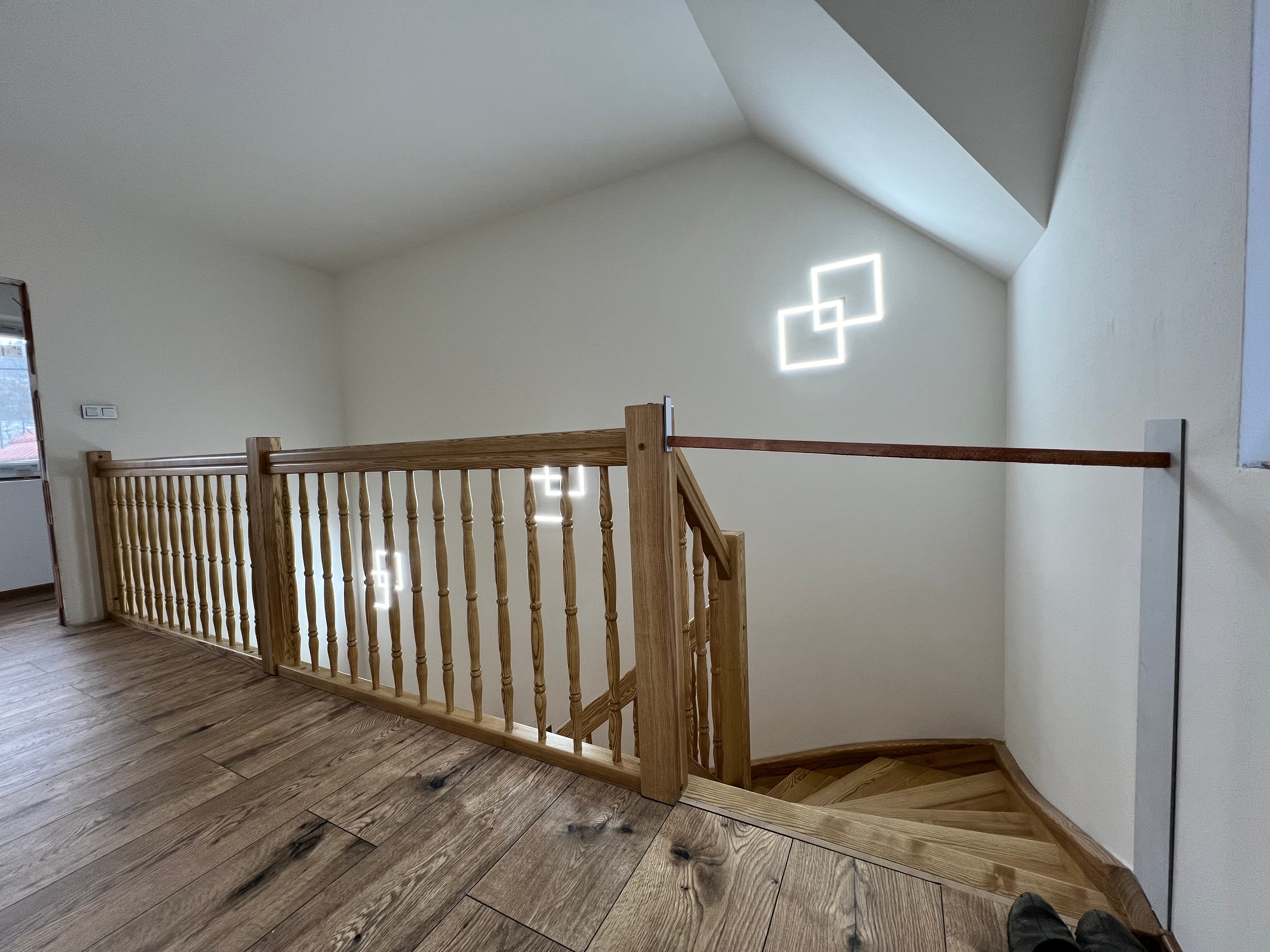 Galerie s točenými balustry a dřevěným zábradlím nad schodištěm