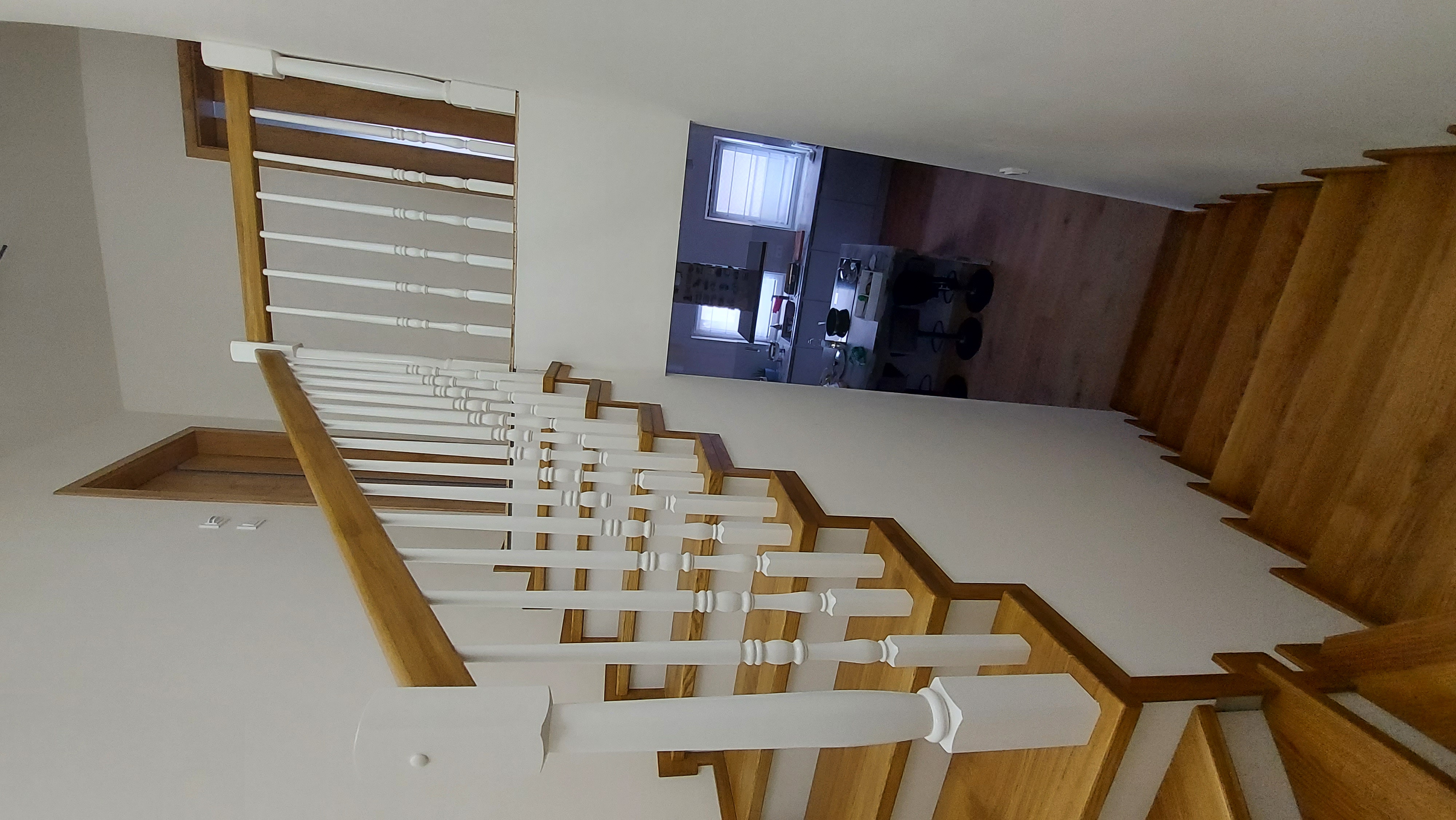 Dubové schodiště s bílými soustruženými balustry a dřevěným madlem
