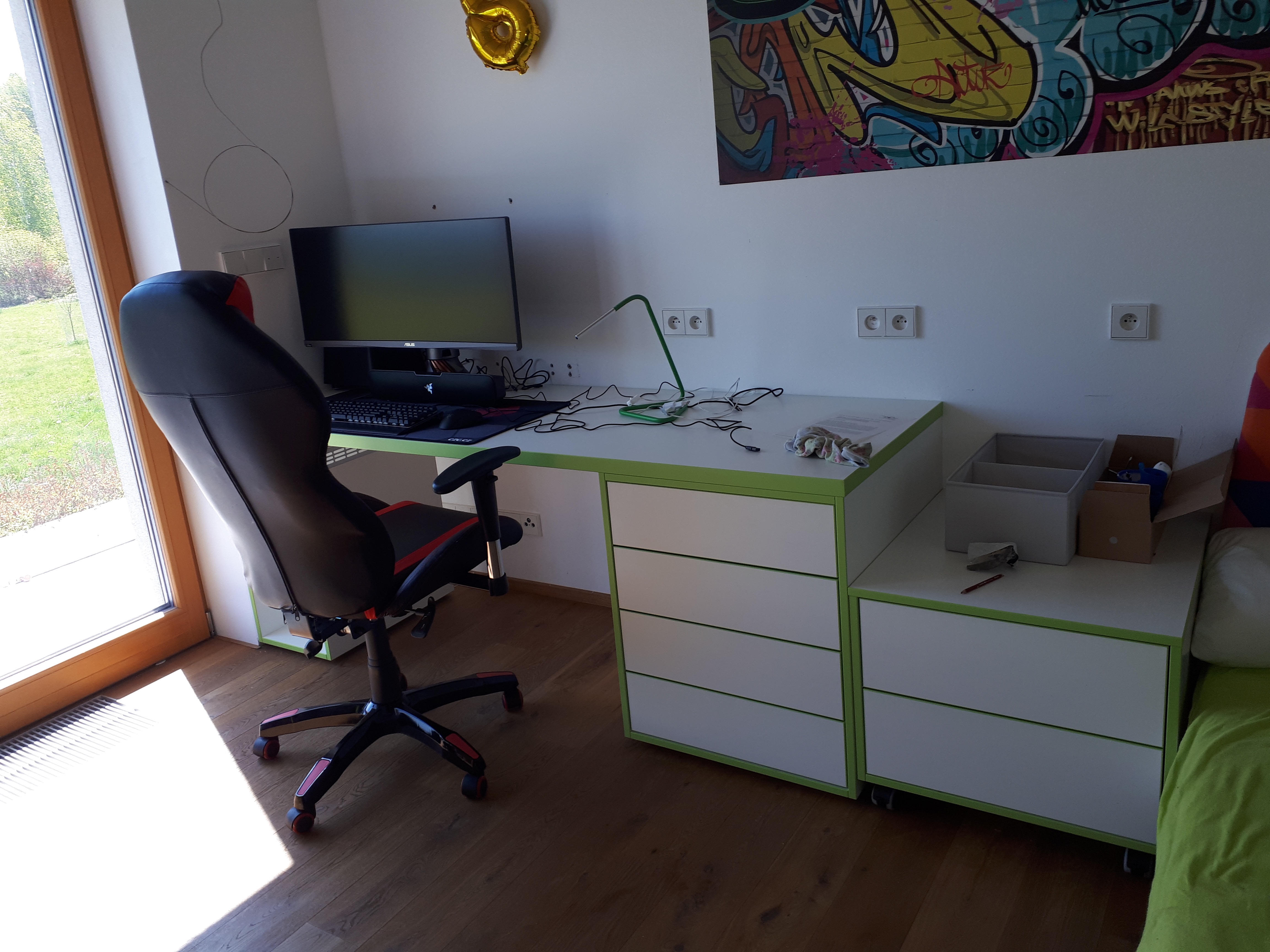 Bílý pracovní stůl se zelenou hranou a pojízdnými zásuvkovými kontejnery